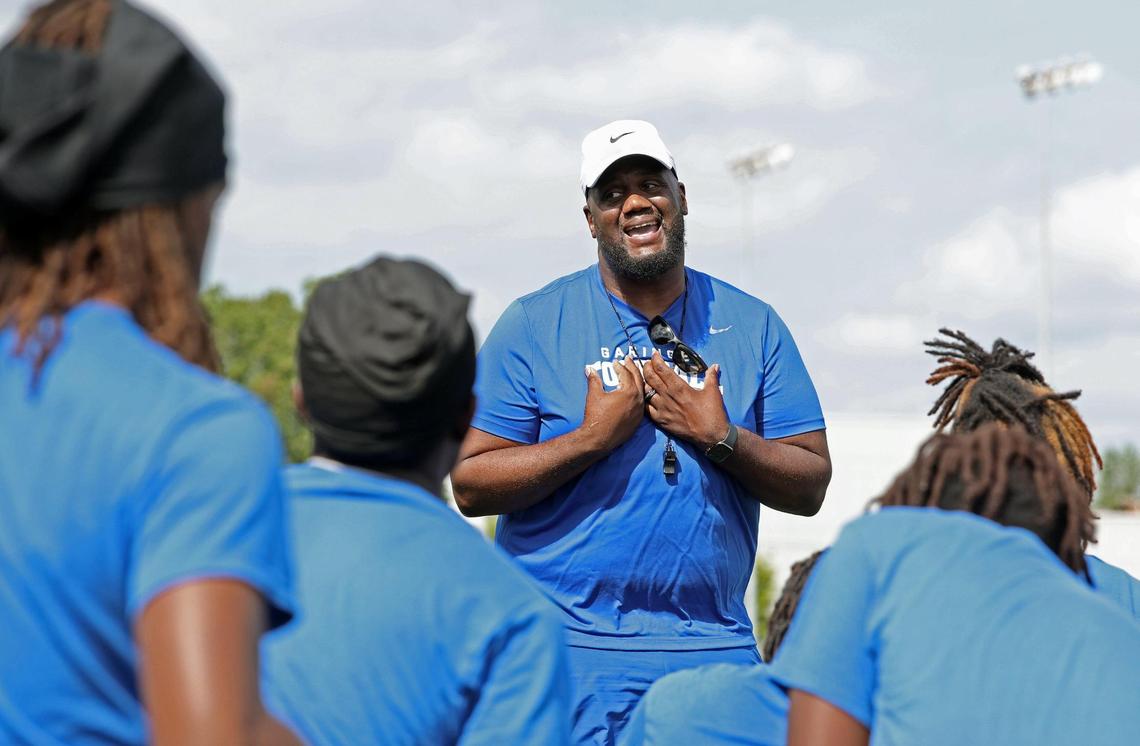 Garinger High School head football coach Jupiter Wilson, center, speaks to his team following a workout on Tuesday, April 29, 2025. Garinger High School has been through dozens of coaches trying to turn the program around. Now, the former UNC football player is taking his turn.