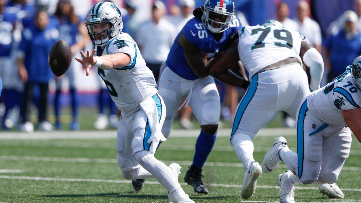 Carolina Panthers quarterback Baker Mayfield, left, pitches the ball during the first half an NFL football game against the New York Giants, Sunday, Sept. 18, 2022, in East Rutherford, N.J. (AP Photo/Noah K. Murray)