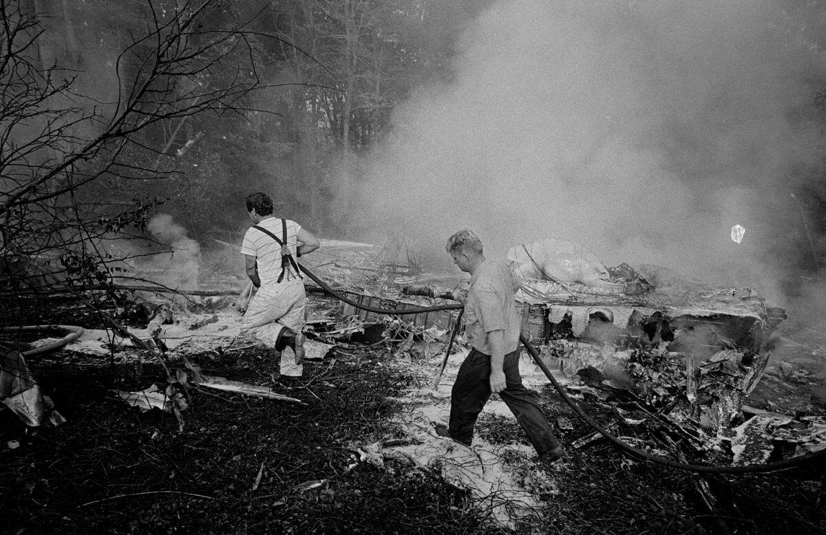 Two unidentified firefighters carry a hose as they continue to work the scene of the crash of Eastern Air Lines Flight 212.