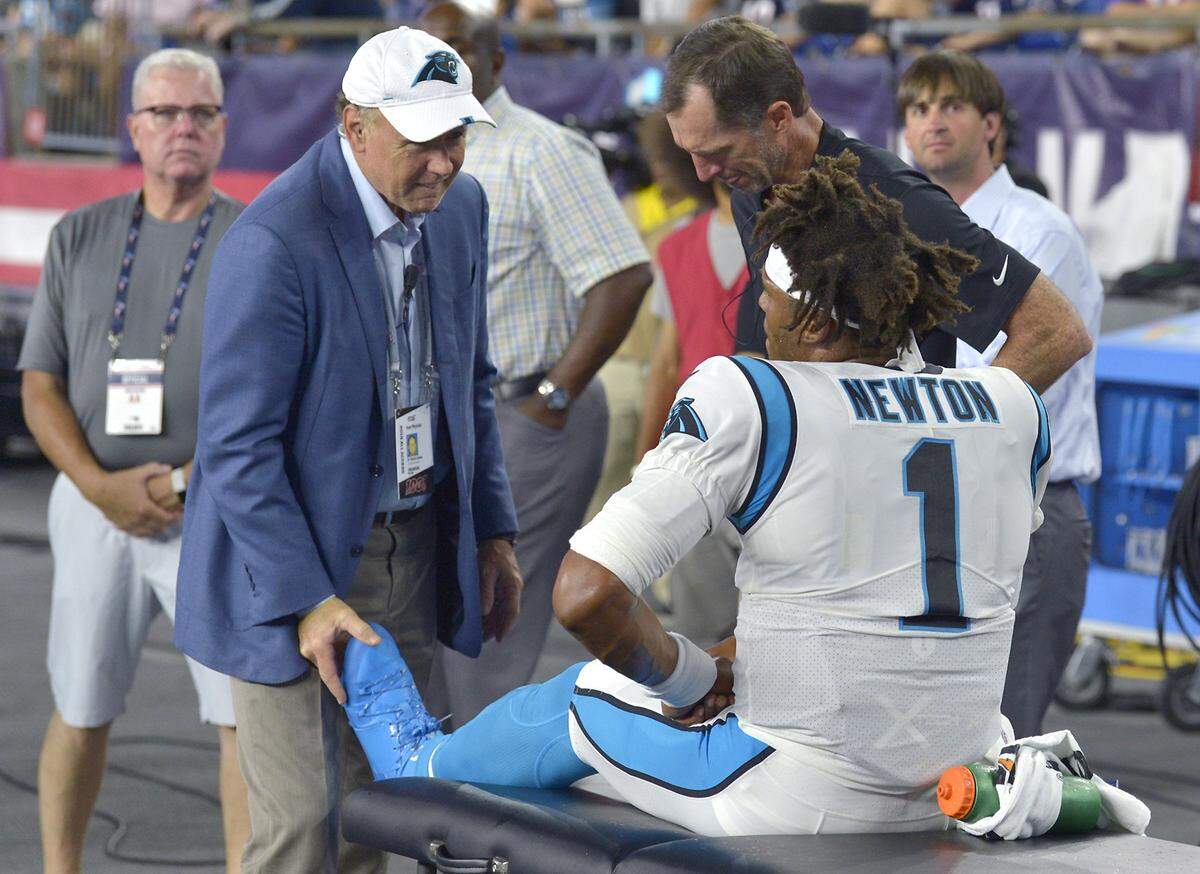 Carolina Panthers medical personnel examine quarterback Cam Newton behind the team’s bench after he injured his left foot during the first quarter against New England Thursday night. It was the first time Newton had faced a live defense since December 2018.