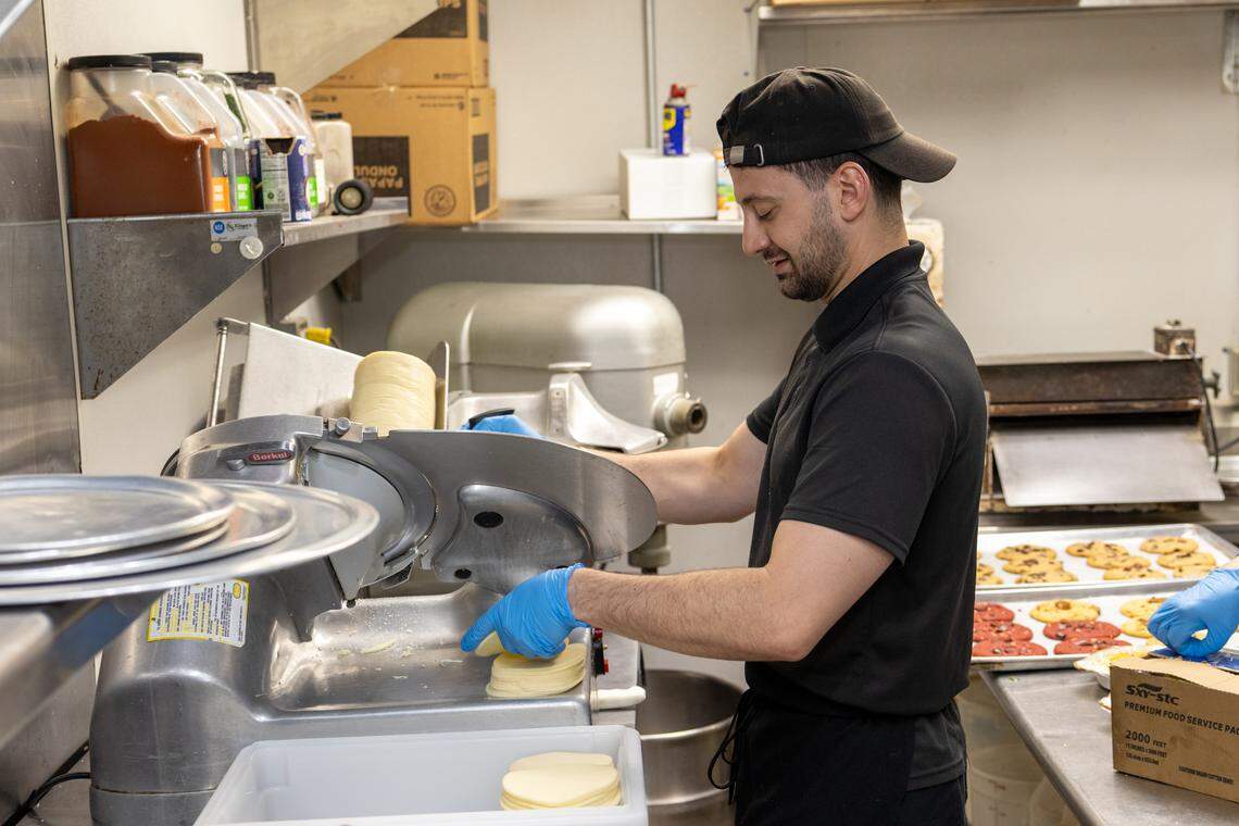 Dean Psilopoulos slices cheese at House of Pizza.