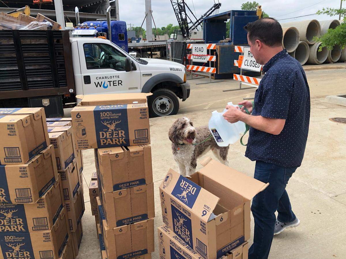 A resident pick up water at the intersection of Duvanant and Hawkins streets in South End on Thursday, May 5, 2022. Repairs to a damaged water main could take several hours, according to the city utility.