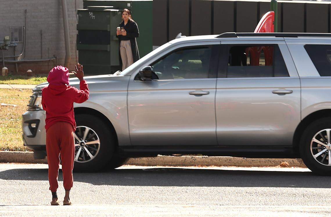 A woman mockingly waves goodbye to U.S. Customs and Border Patrol agents as they leave the Country Club Apartment Homes on Eastway Drive in Charlotte, NC on Tuesday, November 18, 2025. The woman along with others were blowing whistles and yelling for the agents to leave.