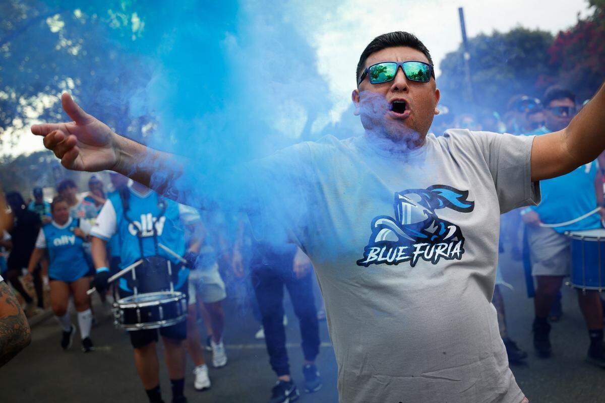 Arturo Vasquez, of Charlotte, N.C., walks through colored smoke while marching with other fans before a game between Charlotte FC and Columbus Crew at Bank of America Stadium in Charlotte, N.C., Saturday, July 30, 2022.