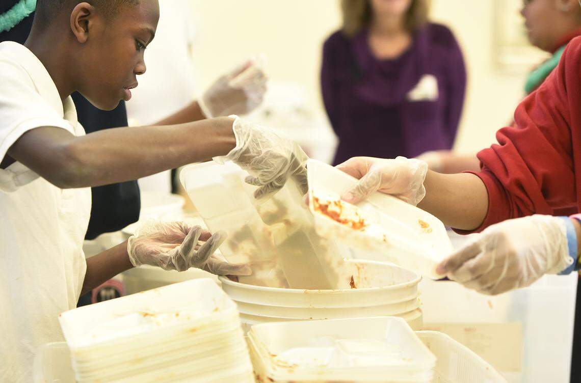 Taishon Marable, 13, dumps uneaten food into a bucket before it gets weighed during a food waste audit at Whitewater Middle School.