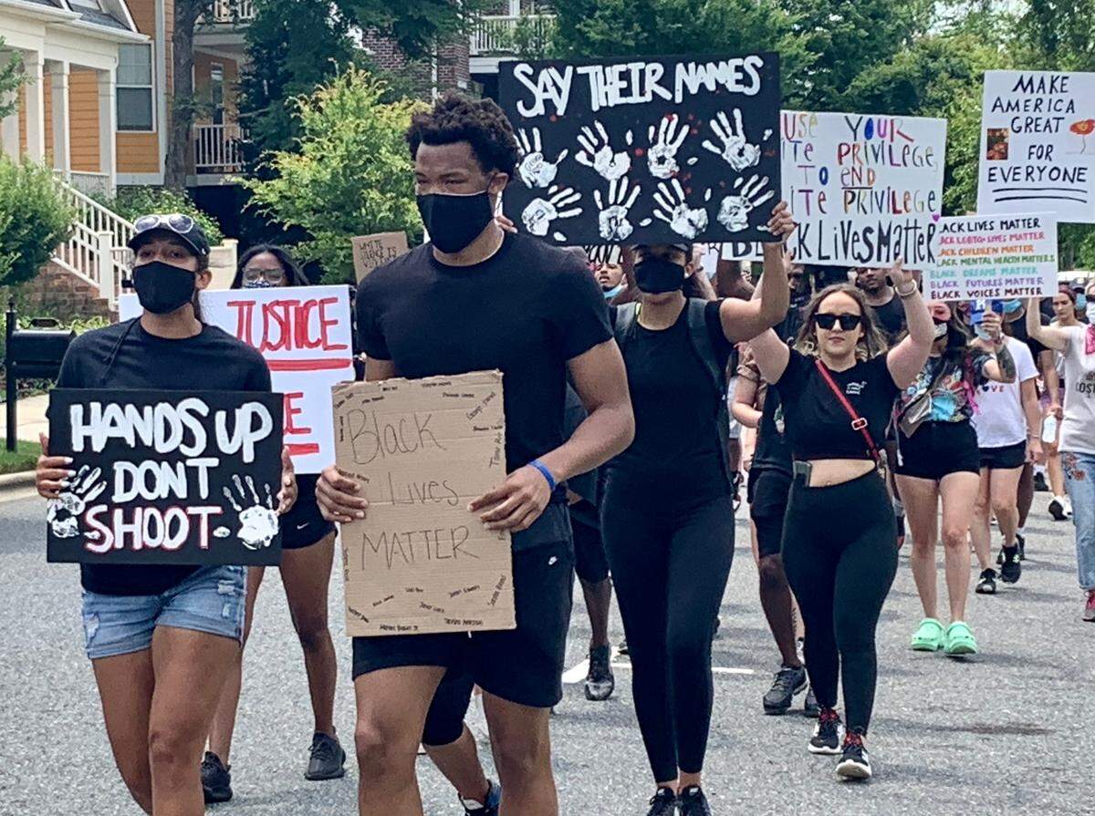 Wendell Moore (center), the current Duke and former Concord Cox Mill basketball star, leads a protest march on Saturday in Concord. Moore and his girlfriend Marissa Moyer (left), inspired by attending a protest in Charlotte, organized the event.