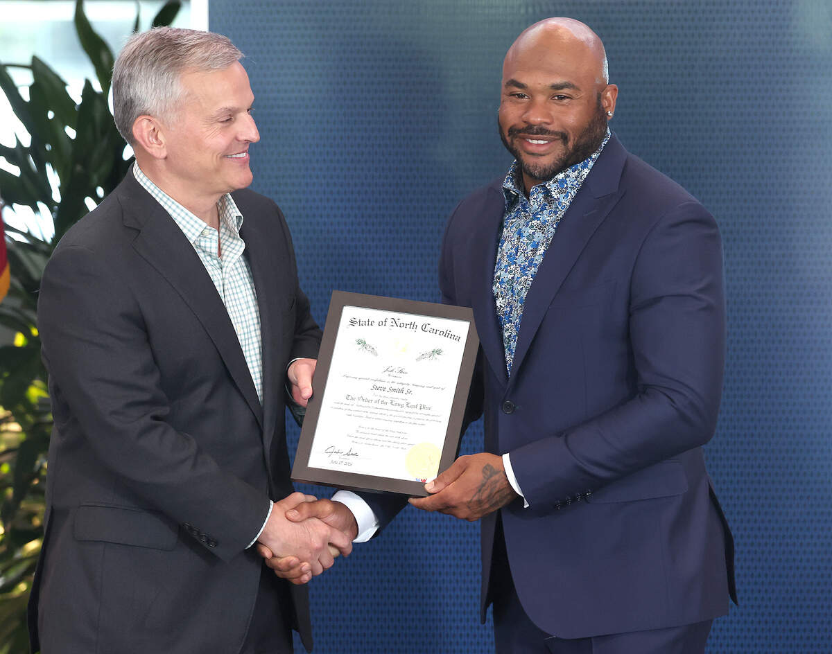 North Carolina Gov. Josh Stein, left, awards former Carolina Panthers wide receiver Steve Smith his certificate to the Order of the Long Leaf Pine at Bank of America Stadium on Wednesday, June 17, 2026. Smith was awarded the honor with other recipients, including Panthers team owner David Tepper.