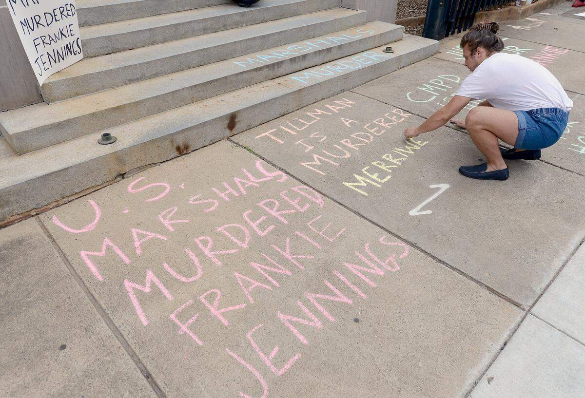 Jamie Marsicano, a community organizer writes on the sidewalk outside the United States Courthouse at 401 W. Trade Street in Charlotte, NC on Tuesday, July 6, 2021. Protesters held a vigil in memory of Frankie Jennings who was shot and killed by a federal marshal on Tuesday, March 23, 2021.