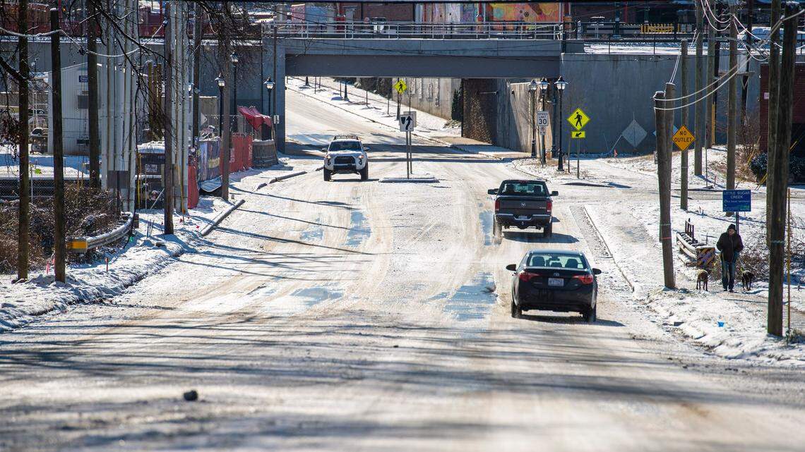 Cars drive down a snow and ice-covered 36th Street on Saturday, January 22, 2022 in Charlotte, NC. After a second snowfall in less than a week, and overnight temperatures in the 20s, roads are icy with frozen snow and black ice.