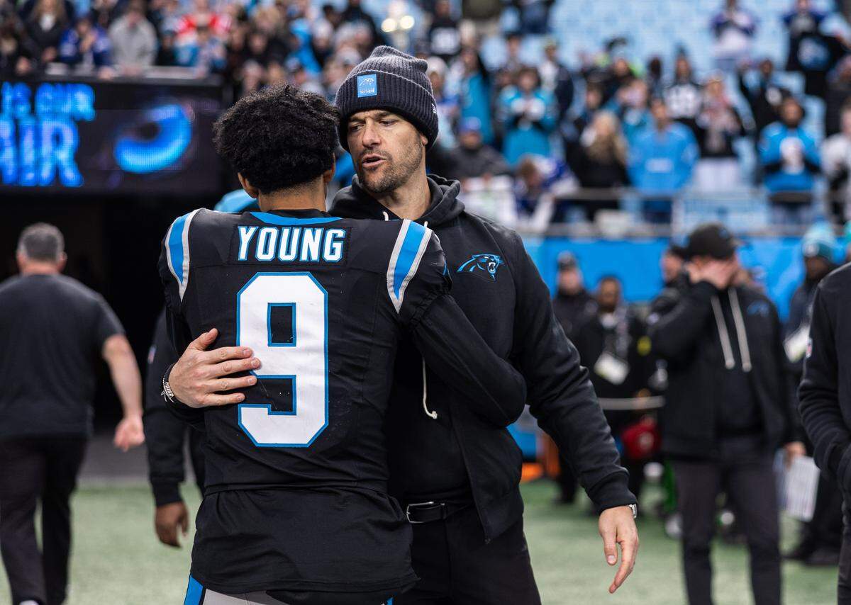 Carolina Panthers coach Dave Canales, right, hugs Carolina Panthers quarterback Bryce Young after their loss against the Seattle Seahawks at the Bank of America Stadium in Charlotte, N.C., on Sunday, December 28, 2025.