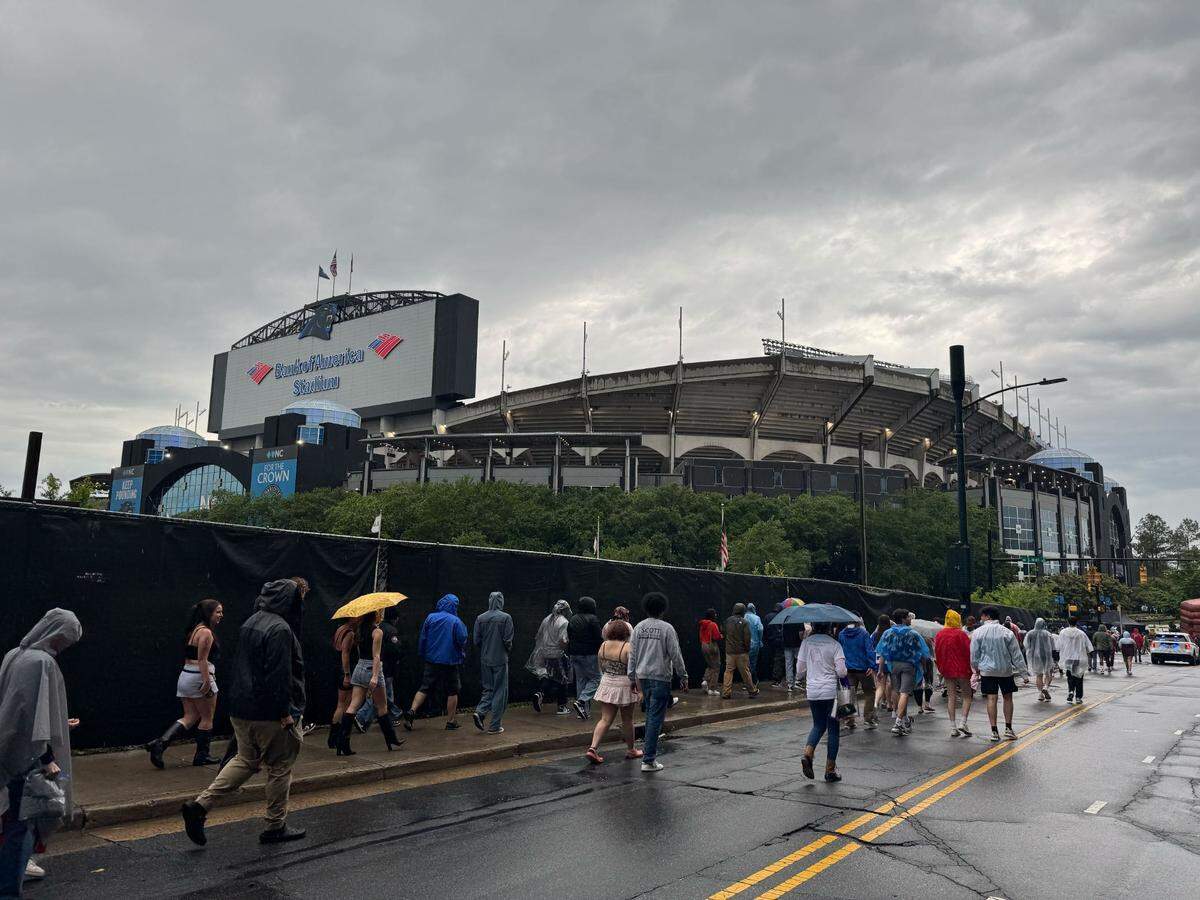 Kendrick Lamar and SZA fans head toward Bank of America Stadium in the rain.