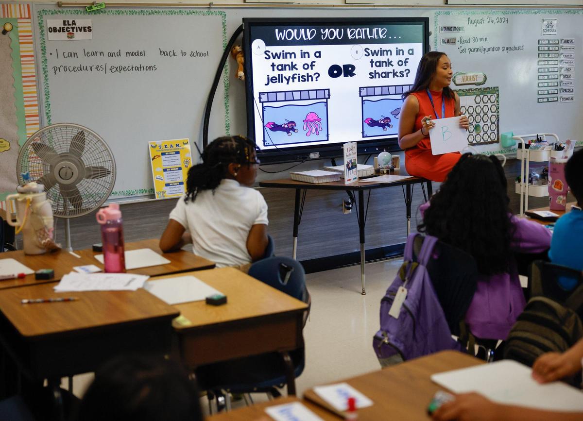 Literacy teacher Caitlyn Westbrook, right, leads fifth graders in a “would you rather...” exercise during the first day of school at Idlewild Elementary School in Charlotte, NC on Monday, August 26, 2024.