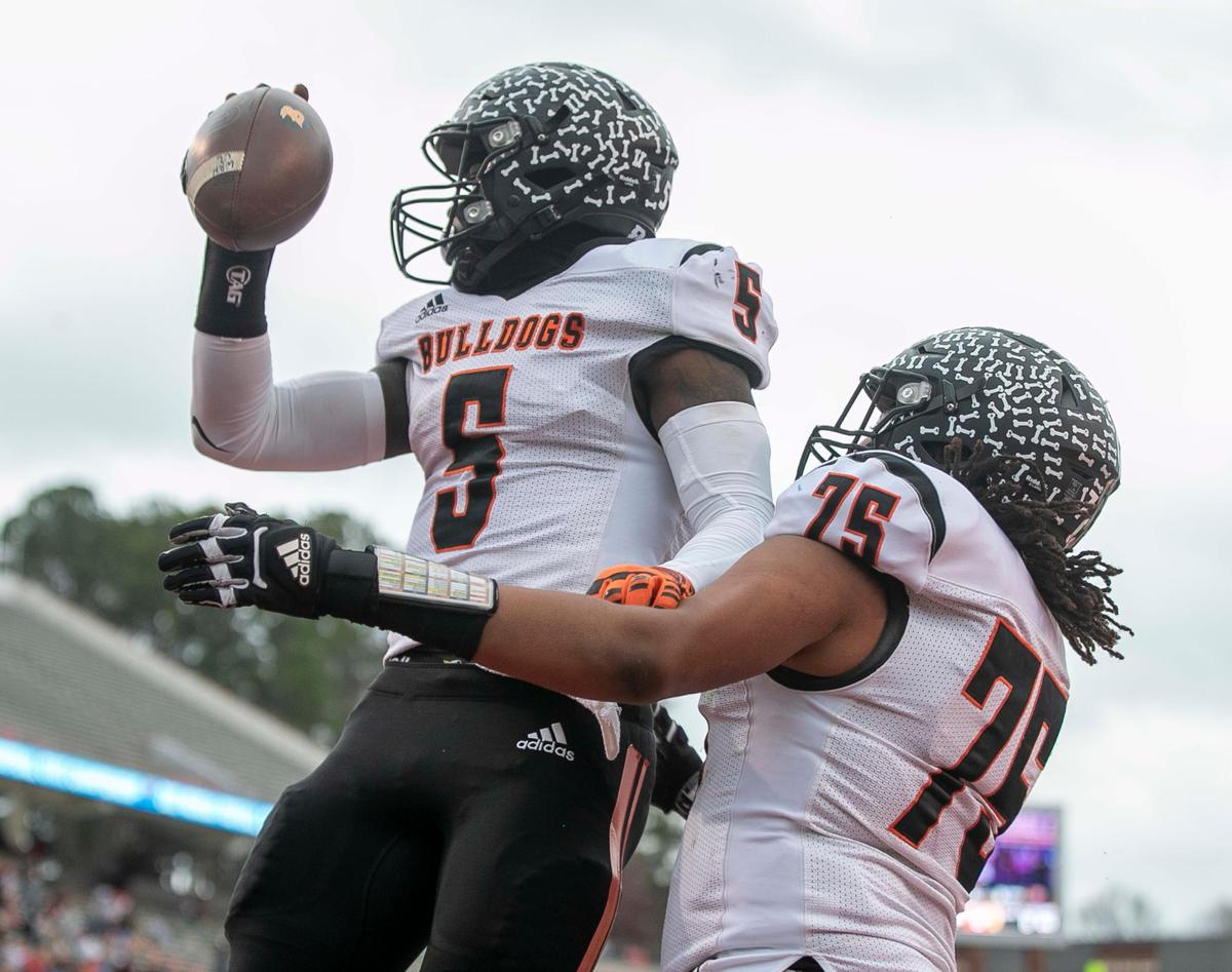Wallace-Rose Hill’s Kanye Roberts (5) celebrates with teammate Arrin McGee (75) after scoring a touchdown in the first quarter against Shelby during the NCHSAA 2-A championship game on Saturday, December 11, 2021 at Carter-Finley Stadium in Raleigh, N.C.
