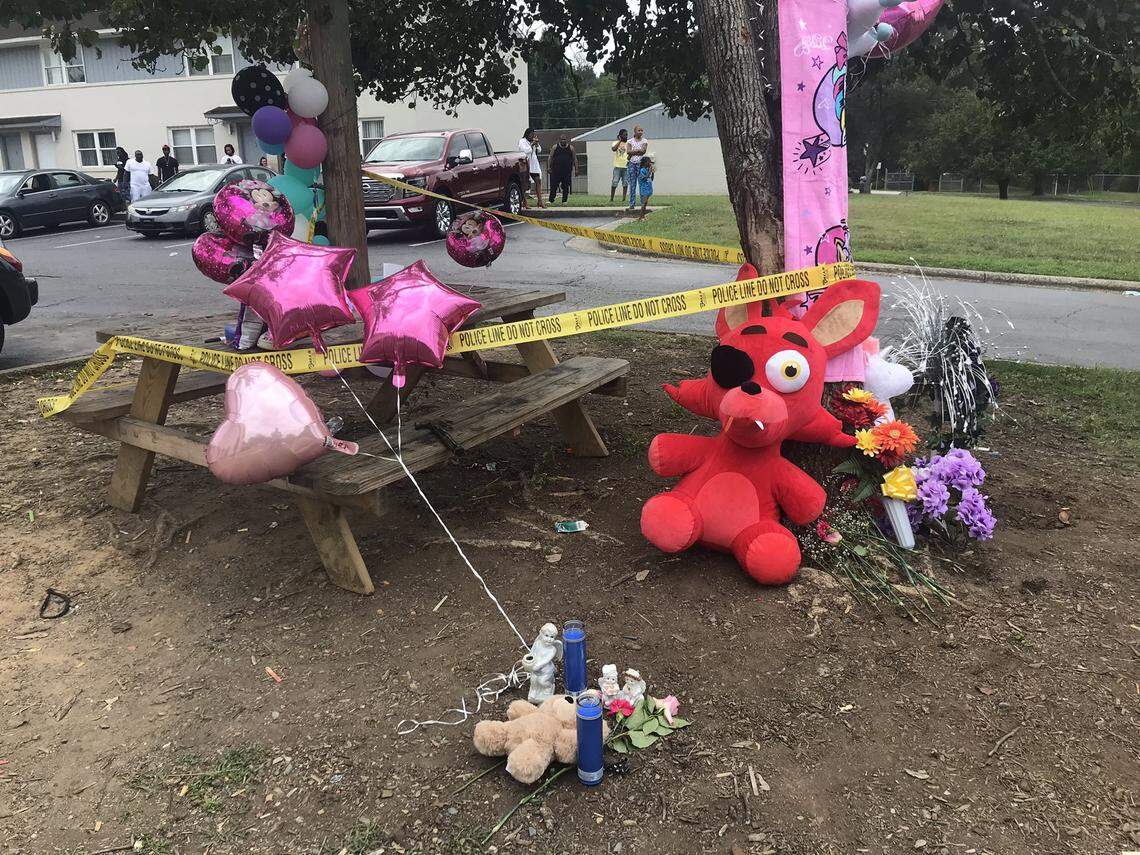Flowers, balloons and stuffed toys serve as a memorial to a 12-year-old child on Sunday, July 25, 2021, a day after the child’s fatal shooting at the picnic table at Icemorlee Street Apartments in Monroe, NC.