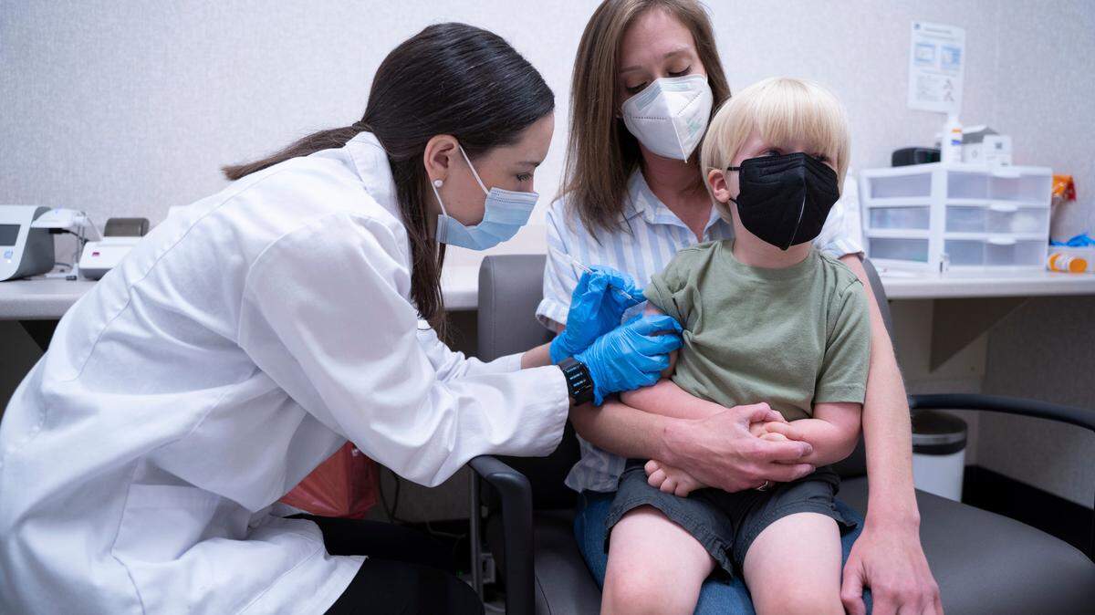 Pharmacist Kaitlin Harring, left, administers a Moderna COVID-19 vaccination to 3-year-old Fletcher Pack of Lexington, SC on June 20, 2022 while his mom, McKenzie Pack, holds him. It was the first day COVID-19 vaccinations were made available to children under age 5 in the US. 