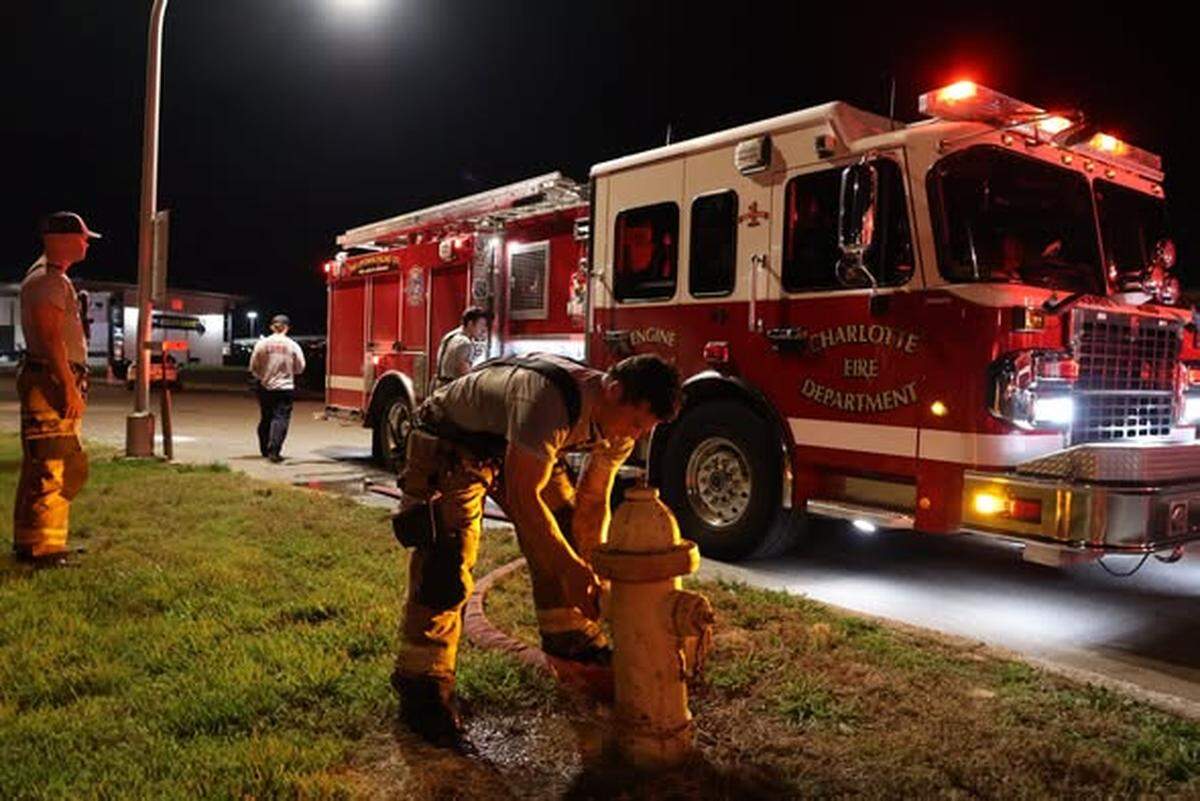 A firefighter secures a hose to a hydrant after an Amtrak train fire in Charlotte on Saturday, May 9, 2026.