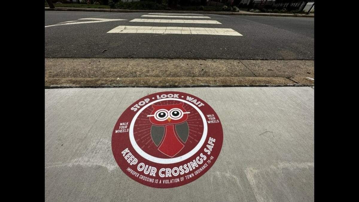 “Friendly owl” sidewalk stickers alert walkers to pedestrian safety zones at traffic-heavy street crossings in the town of Davidson, N.C.