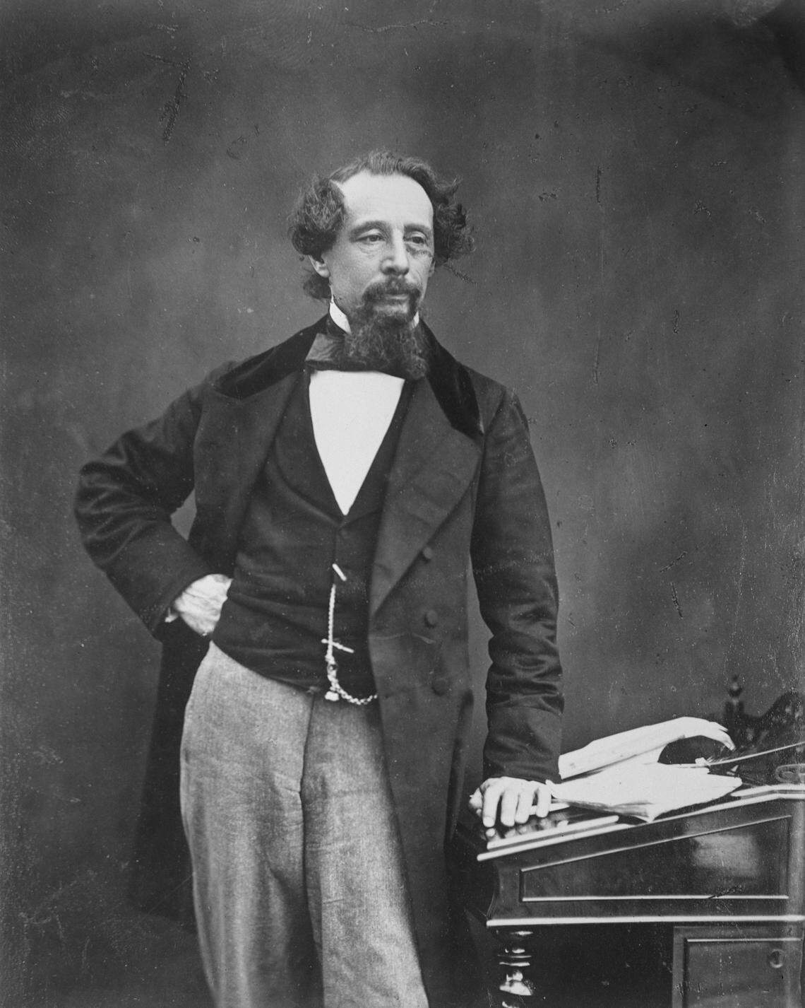 English author Charles Dickens (1812 - 1870) standing with one hand on a writing desk, circa 1860. (Photo by Rischgitz/Hulton Archive/Getty Images)