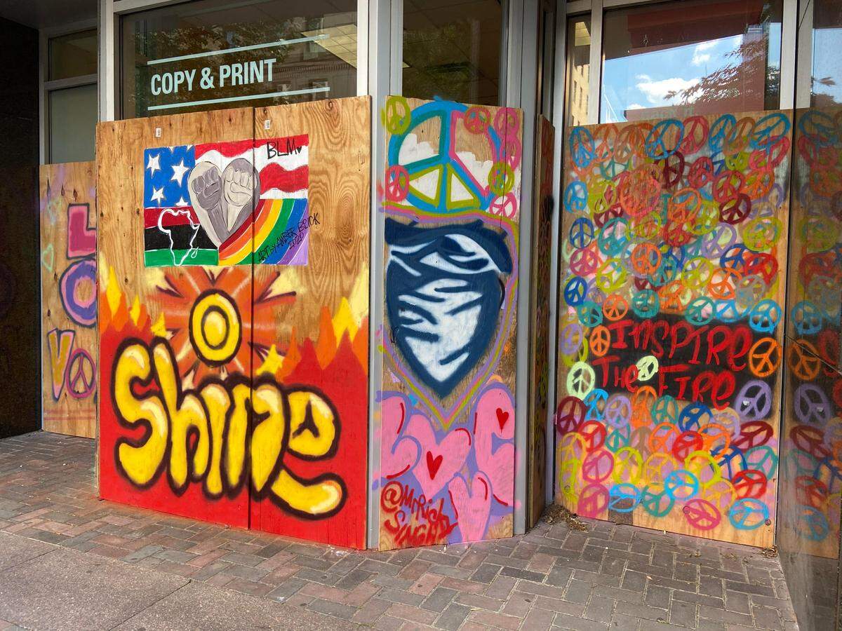 Photo of art depicting the CMPD shield on boarded-up windows along S. Tryon Street.