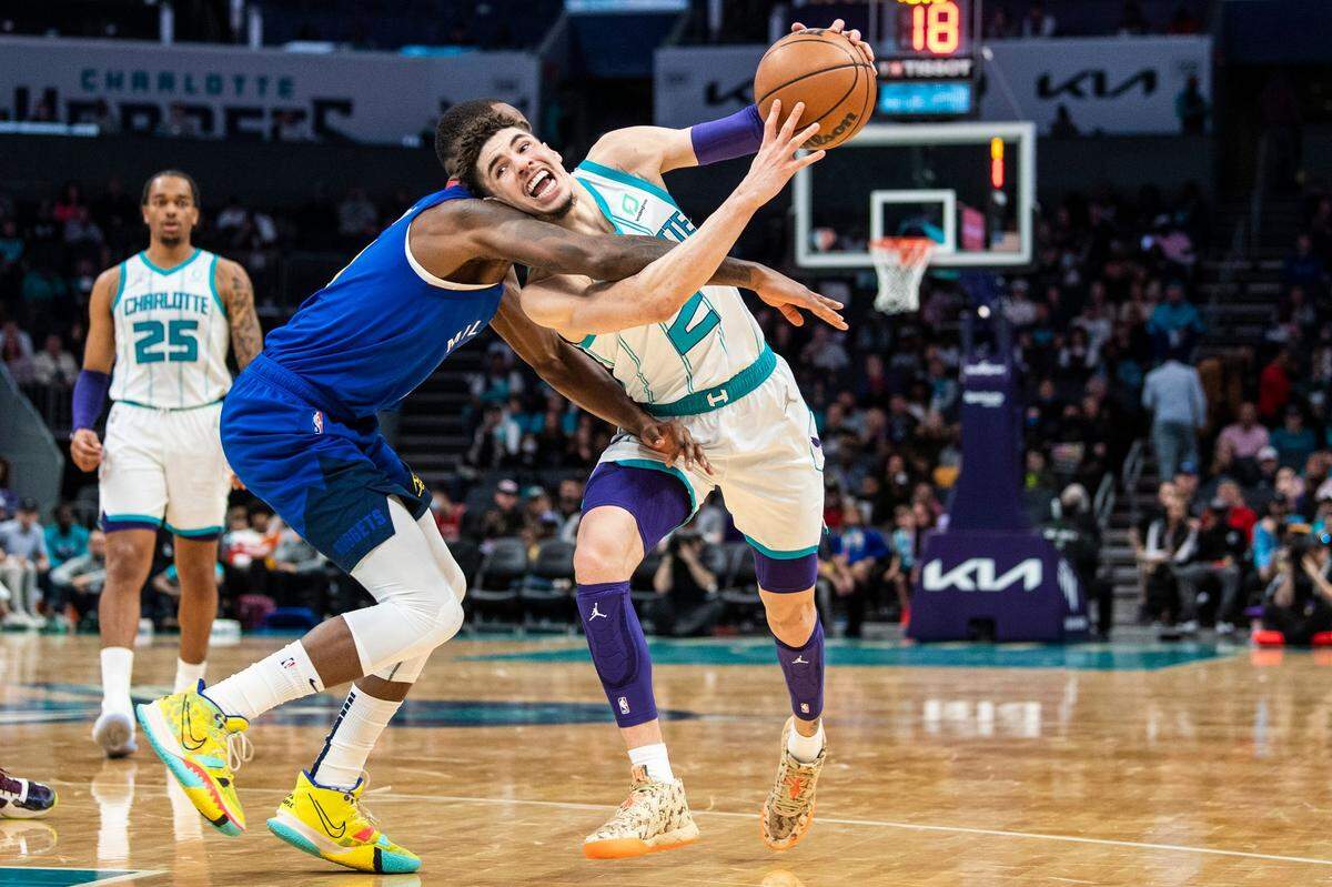 The Hornets LaMelo Ball, right, struggles against defense by the Nuggets Davon Reed during the game at Spectrum Center on Monday, March 28, 2022 in Charlotte, NC.