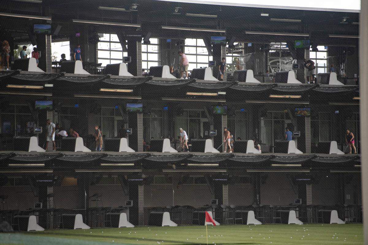 Guests play golf in separate bays at TopGolf in Charlotte. TopGolf now sanitizes all bays and equipment after each use.