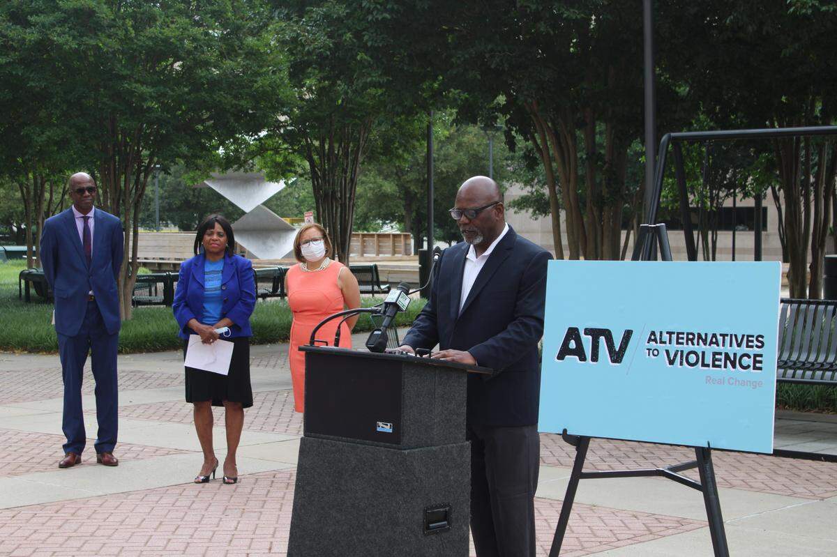 George Dunlap, Mecklenburg County commissioner chair, unveiling the name of the city and county’s new violence interrupter program “Alternatives to Violence” on Tuesday in front of the Charlotte-Mecklenburg County Government Center.