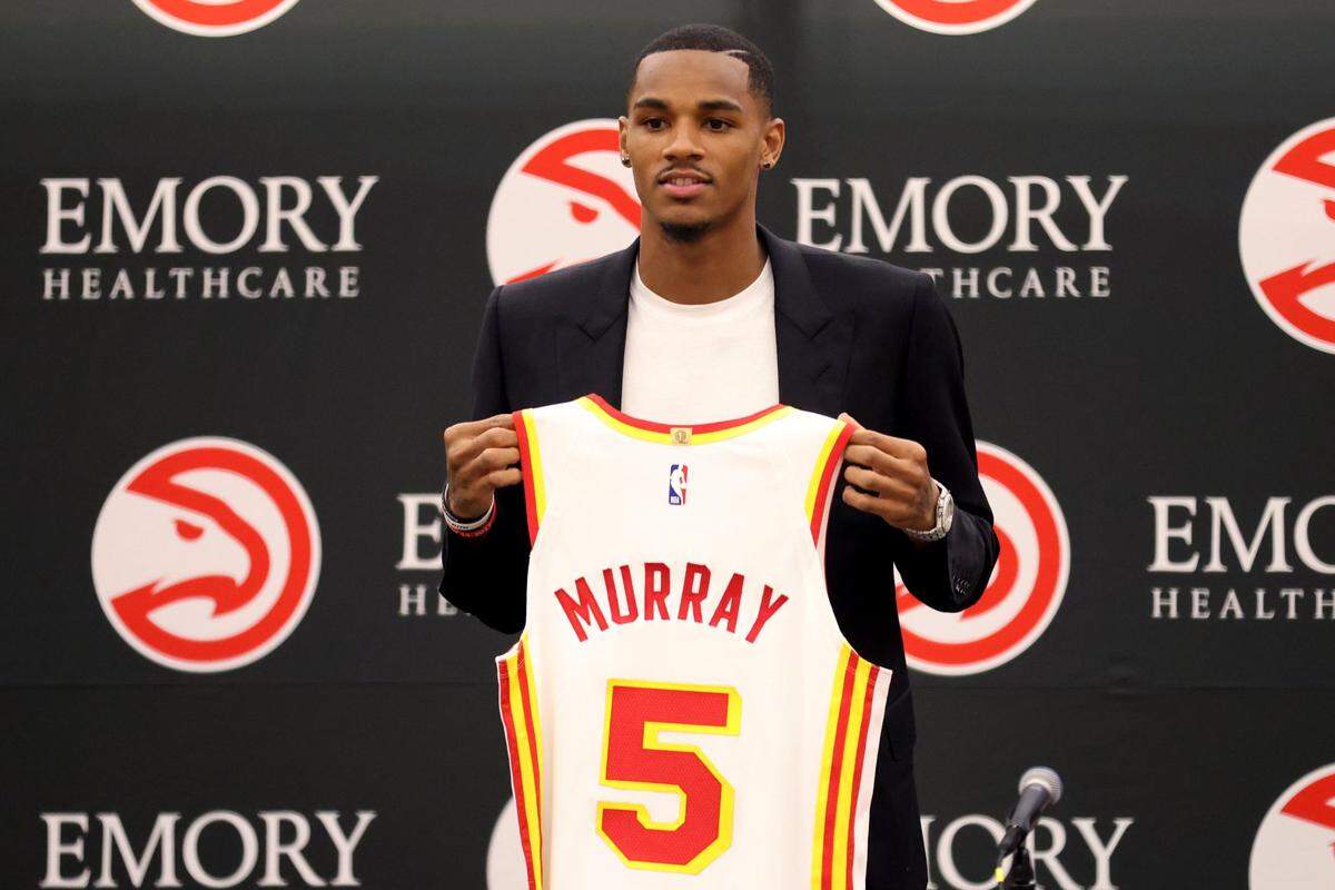 Atlanta Hawks guard Dejounte Murray holds a jersey during an NBA basketball press conference at the Emory Sports Medicine Complex, Friday, July 1, 2022, in Atlanta. (Jason Getz/Atlanta Journal-Constitution via AP)