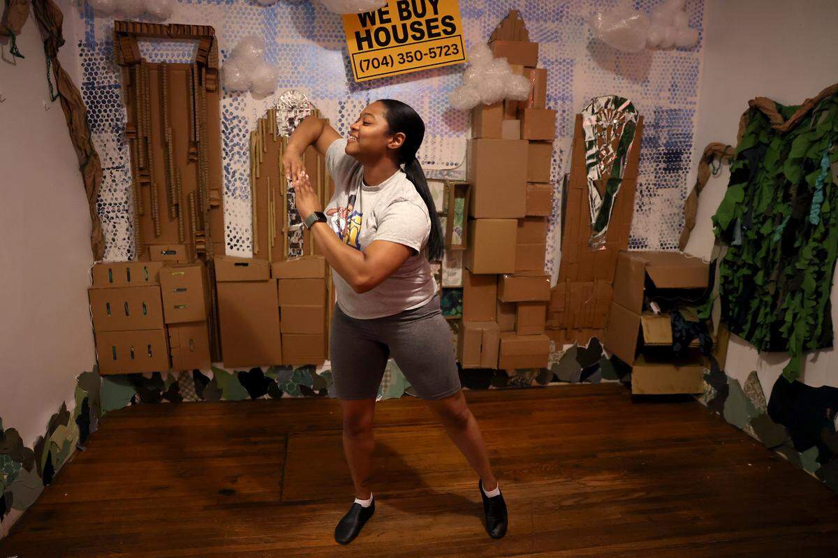Cecilia McNeill, left, portraying the character Goddess dances during a rehearsal on Tuesday, August 13, 2024 at the QC Family Tree’s Big Blue House in Charlotte, NC. McNeill is acting in an immersive play on gentrification.
