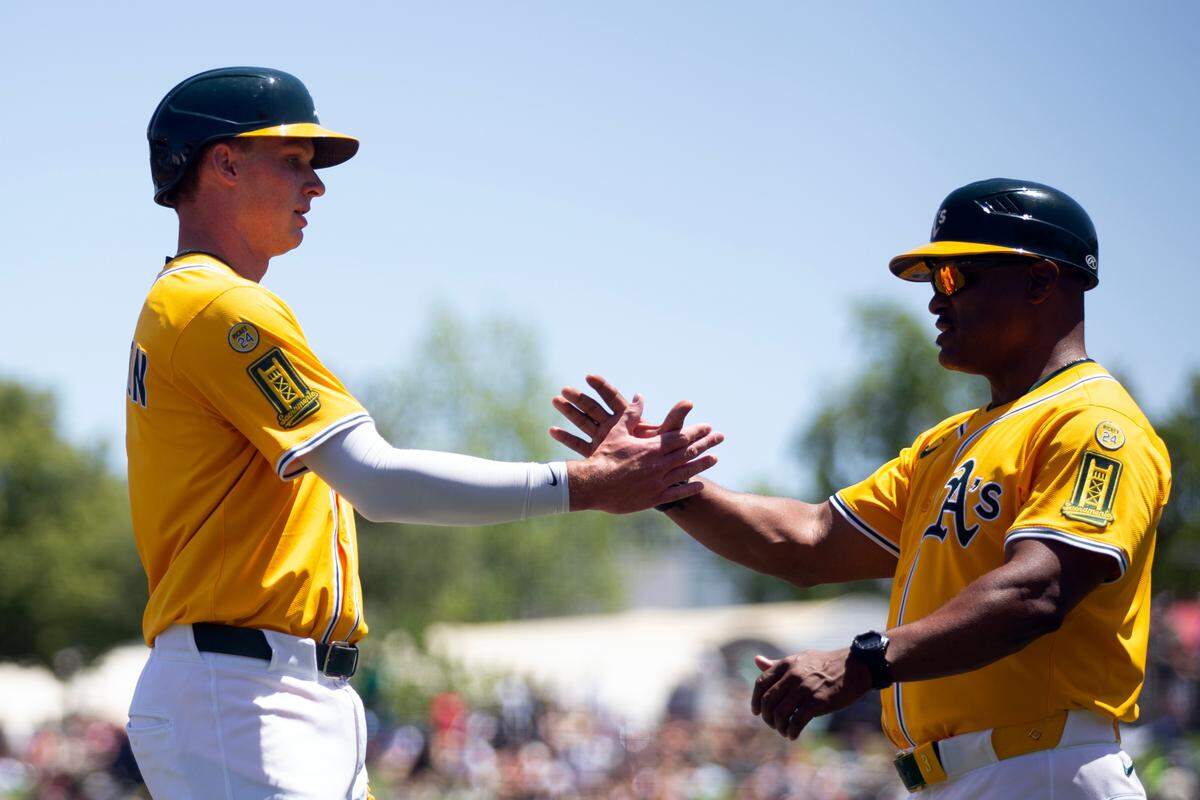 Athletics first baseman Logan Davidson (6) gets a congratulatory handshake from third-base coach Eric Martins after getting his first hit and RBI against the Philadelphia Phillies during a late May game at Sutter Health Park. D. Ross Cameron-Imagn Images