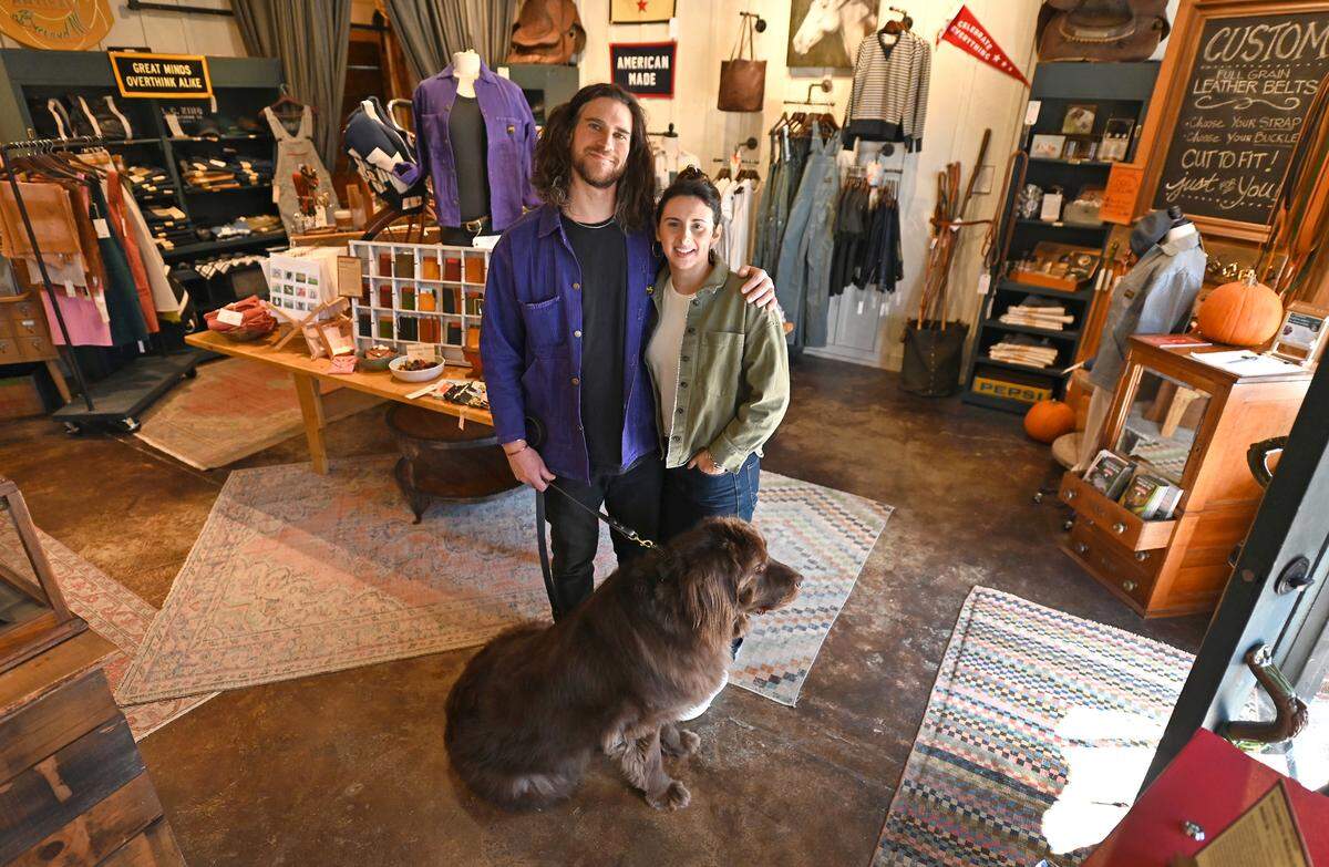 Doug and Emma Miller pose with their dog, Victor at their Newfound Artisan store in Brevard, NC on Friday, November 15, 2024. Following Hurricane Helene the couple says that they have seen nearly a 30% decrease in sales compared to last year.