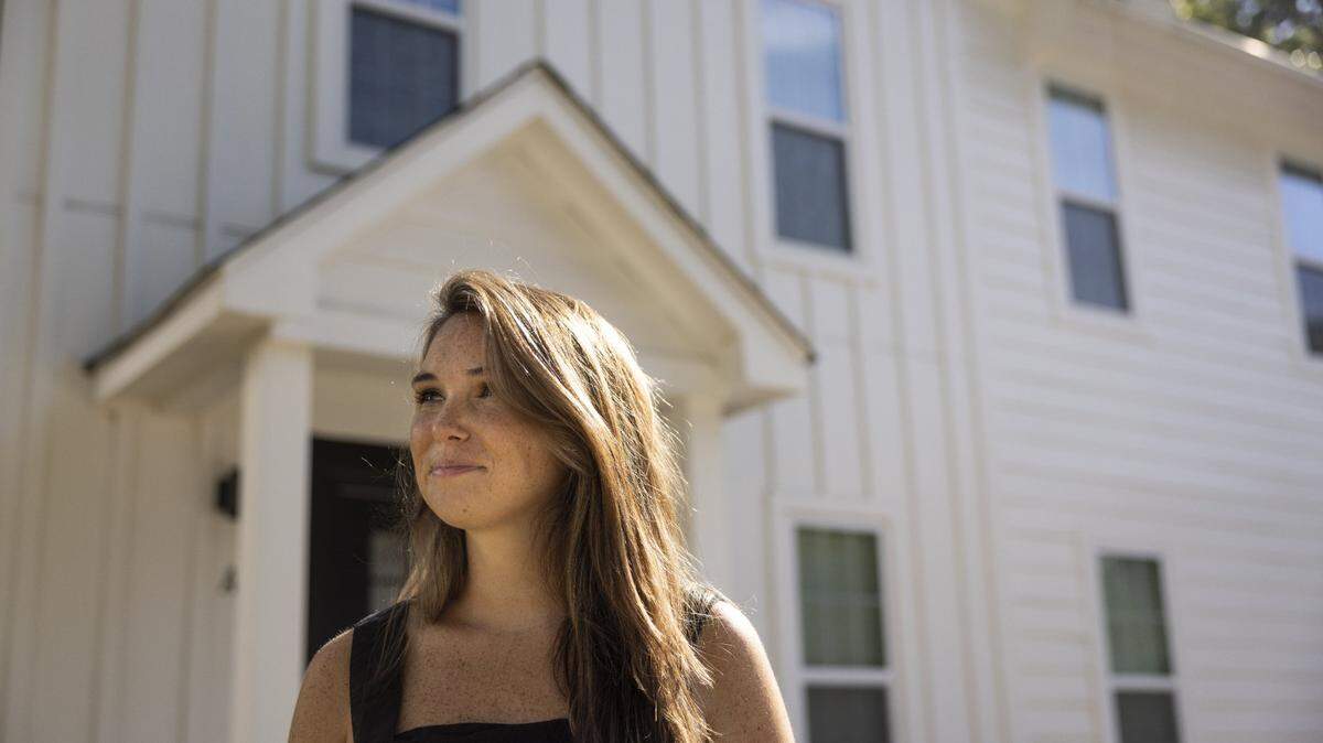 Brianna Hourihan stands outside of the house that she owns a unit in in Charlotte, N.C., on Friday, July 15, 2022. Hourihan was able to make an all-cash offer on this home using a service called Ribbon.