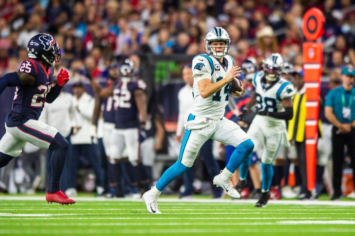 Panthers quarterback Sam Darnold, right, sticks his tongue out as he runs the ball on a quarterback keeper as Texans defense back Desmond King, II, pursues during the game at NRG Stadium on Thursday, September 21, 2021 in Houston, TX. The Panthers beat the Texans 24-9, giving them their third win in a row to start the season.