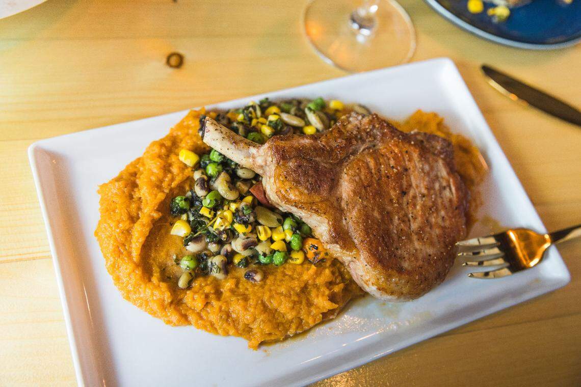 The pork chop at 204 North Kitchen and Cocktails is served with sweet potato puree and summer vegetable succotash.