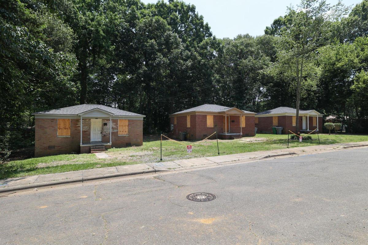 Small houses, situated on Jennings Street, have boarded windows and warnings to not park nearby.