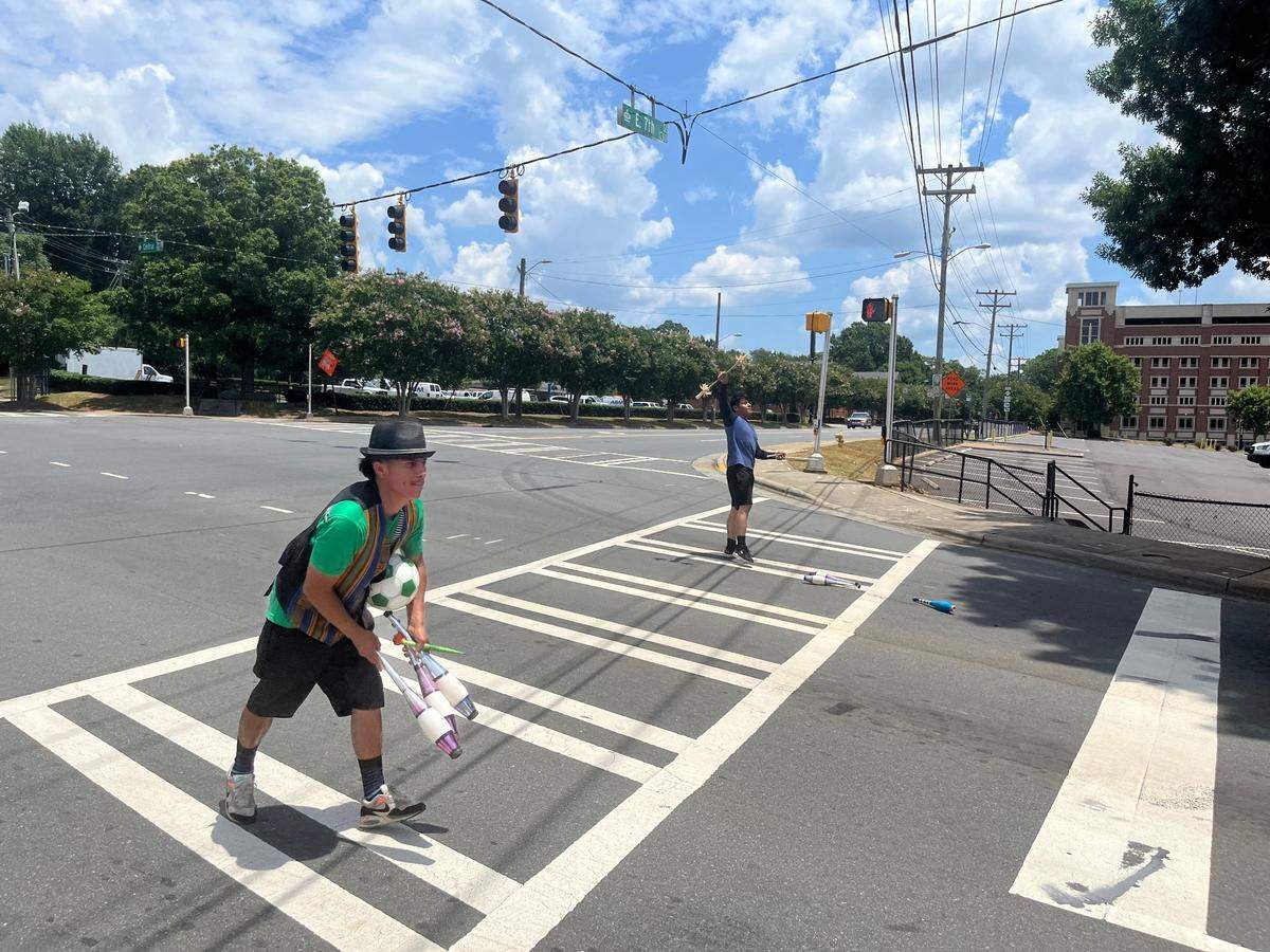 Erick Valentin, right, and his roommate juggle at the intersection of North Kings Drive and East 7th Street near uptown Charlotte on July Fourth, hoping to earn appreciation — and cash — from motorists stopped at a red light.