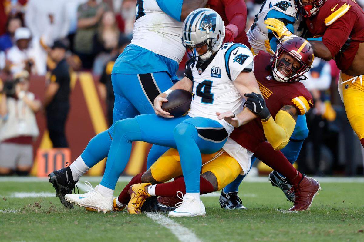 Carolina Panthers quarterback Andy Dalton (14) is sacked by Washington Commanders linebacker Frankie Luvu (4) during the second quarter at Northwest Stadium on Oct 20, 2024.