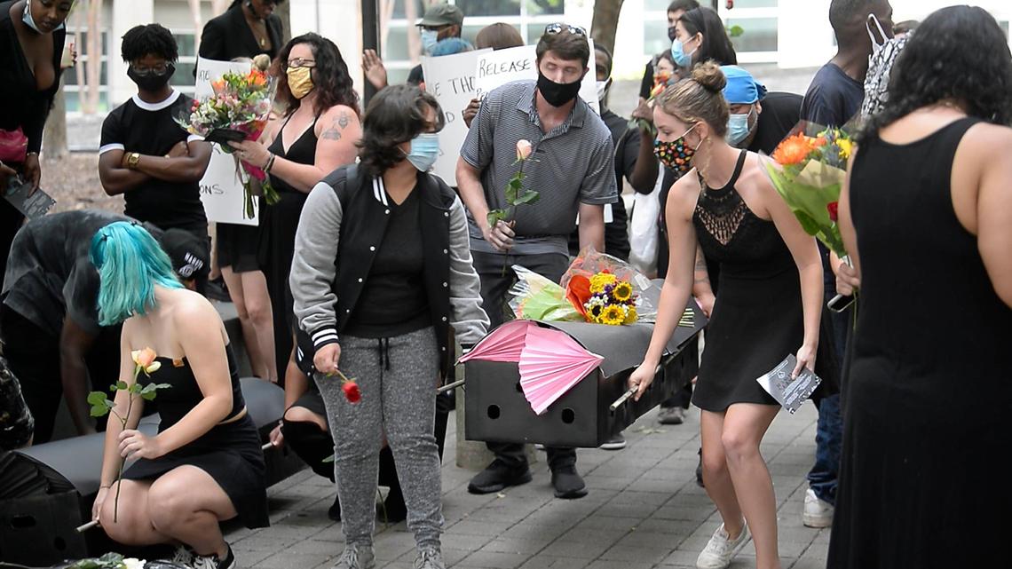 Participants in a protest organized by Decarcerate Mecklenburg, called Funeral Friday, carry flowers and boxes representing coffins during part of a memorial to honor those who have died from coronavirus while being incarcerated, on Friday, August 7, 2020.