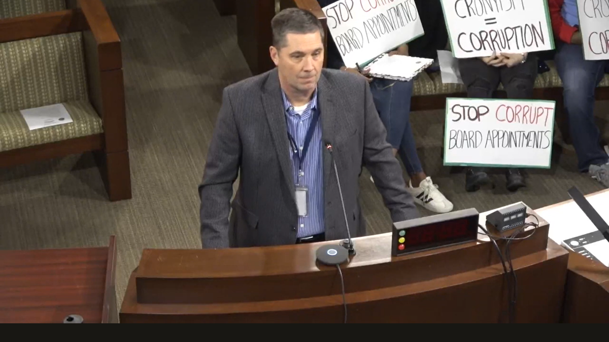 People hold signs opposing Shannon Lancaster’s board appointments at a Cabarrus County Board of Commissioners work session on Feb. 3, 2025.
