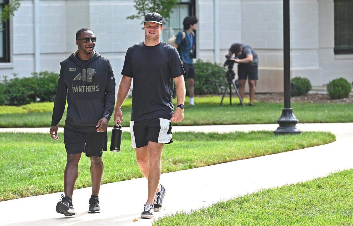 Carolina Panthers employee Chris Brannon, left, and and quarterback Sam Darnold walk to a press conference outside the team’s dorm at Wofford College in Spartanburg, S.C., on Tuesday, July 26, 2022. The team’s first practice will be Wednesday, July 27, 2022.