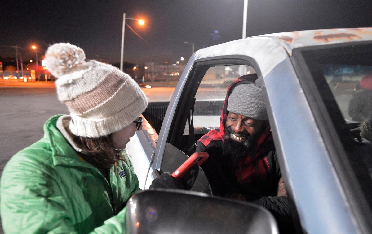 Homeless men living in a truck receive supplies from volunteer Katy Harrell, left. Volunteers in small groups will headed out on the streets before dawn Thursday to count the number of homeless people in Mecklenburg County.
