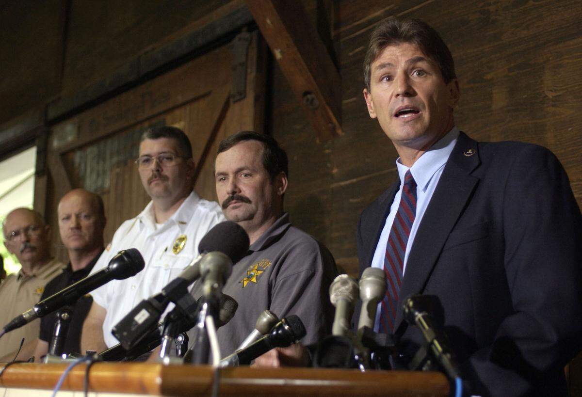 FBI agent Chris Swecker (R) answers a question from the media during a press conference in Murphy, North Carolina, May 31, 2003. Behind Swecker are Murphy chief of police Mark Thigpen (3rd L) and Cherokee County Sherriff Keith Lovin (2nd R). A 21-year-old rookie police officer, on the job for less than a year, apprehended the FBI’s most notorious fugitive, Eric Robert Rudolph. Rudolph, 36, had been hiding out for five years in the mountains of North Carolina, apparently using his skills as an outdoorsman to evade agents anxious to bring him to book for the 1996 Atlanta Olympics bombing. He is also suspected of bombing abortion clinics and a gay nightclub. REUTERS/Alan Mothner