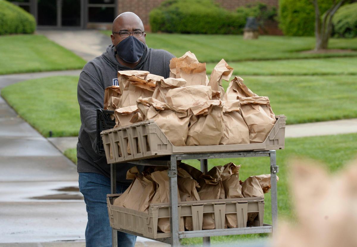 Charles Robinson, a minister at Bread of Life Deliverance Church and executive director of the non-profit Community Hub 1245, rolls out a cart of lunch bags for delivery to families in north and northeast Charlotte. The meals were prepared at Northside Baptist Church on Monday, April 20, 2020.