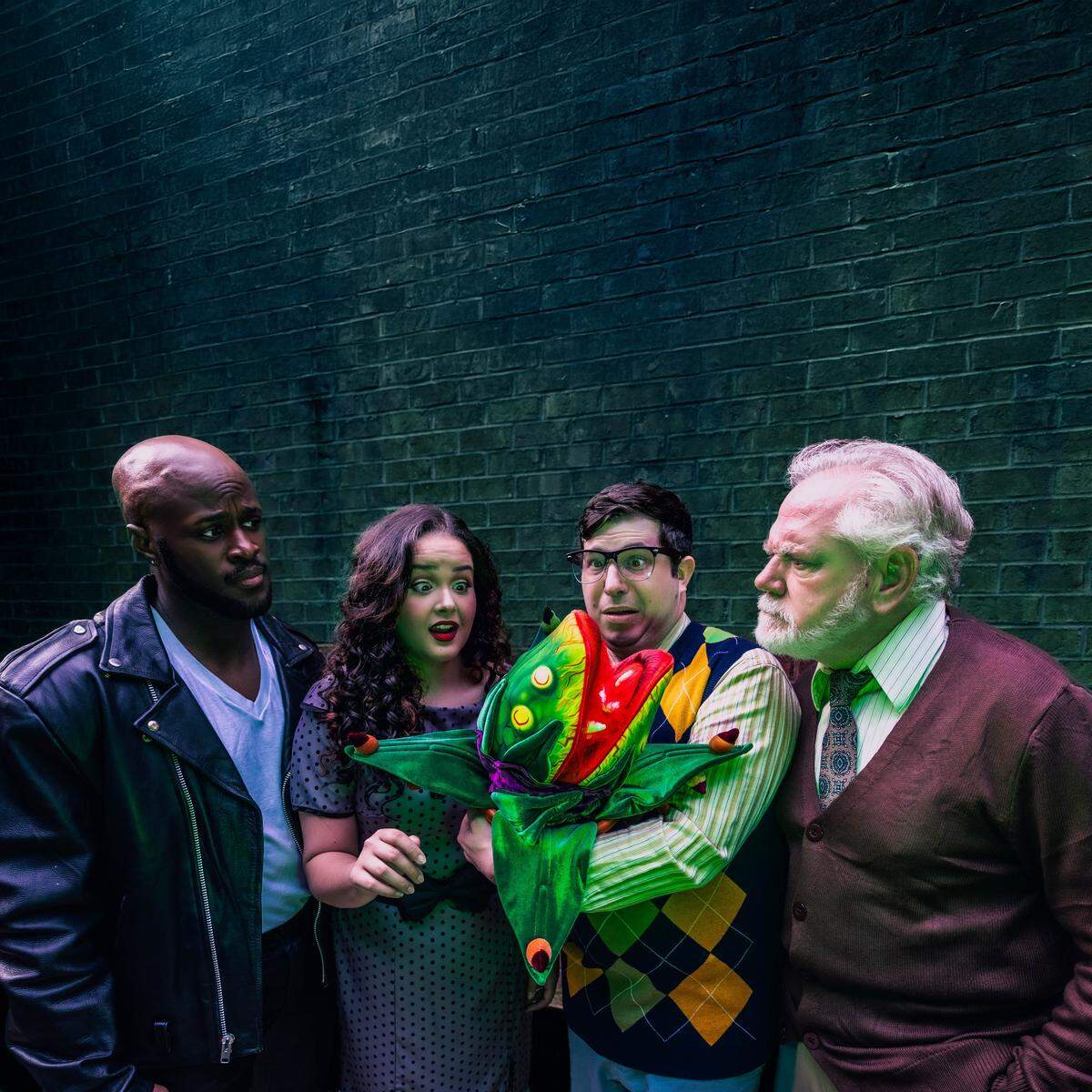 The cast of Theatre Charlotte’s “Little Shop of Horrors,” down on Skid Row, from left, real-life dentist Dr. Nehemiah Lawson as sadistic dentist Orin, Gabriella Gonzalez as Audrey, seeking somewhere that’s green, Audrey II (with the killer voice of Toni “Aideem” Morrison), Peter Liuzzo as Seymour, a budding botanist, and Kevin Roberge as plant shop owner/entrepreneur Mr. Mushnik.
