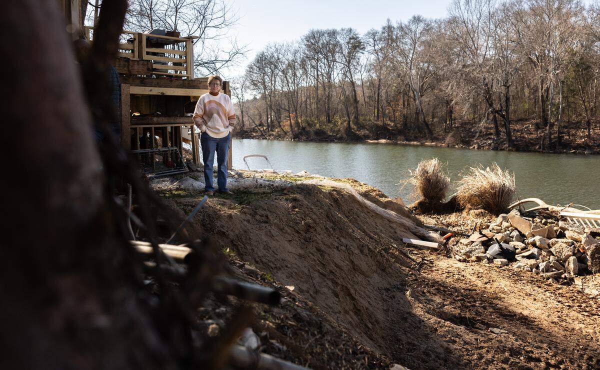 “I cried for a solid month, ‘cause what do you do? You just cry,” says Betsy Patton, whose Riverhaven Drive home was narrowly spared major flood damage. Here, she stands next to her neighbor’s land — which was washed away along with the home itself.