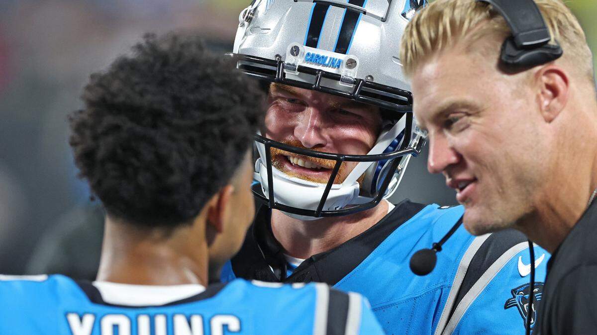 Carolina Panthers quarterback Bryce Young, back to camera, talks with quarterback Andy Dalton, center, and quarterbacks coach Josh McCown, right, during second quarter action against the Detroit Lions on Friday, August 25, 2023 at Bank of America Stadium in Charlotte, NC.