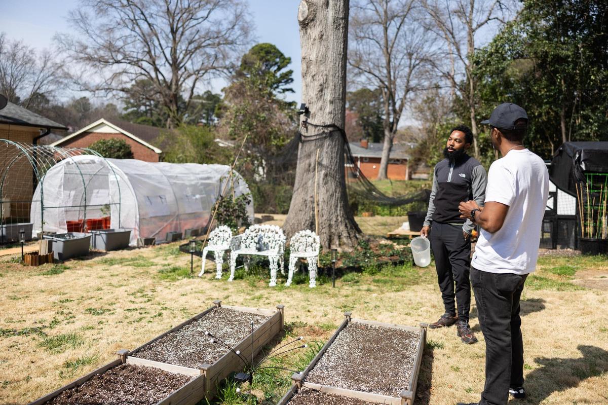 Austin McCathorine, left, talks with Sean Langley in his McCrorey Heights backyard. McCathorine brought up concerns about emissions coming from the highway potentially harming his chickens and garden. They are also worried about funding cuts from the Environmental Protection Agency, which could lead to less air quality monitoring in Charlotte.