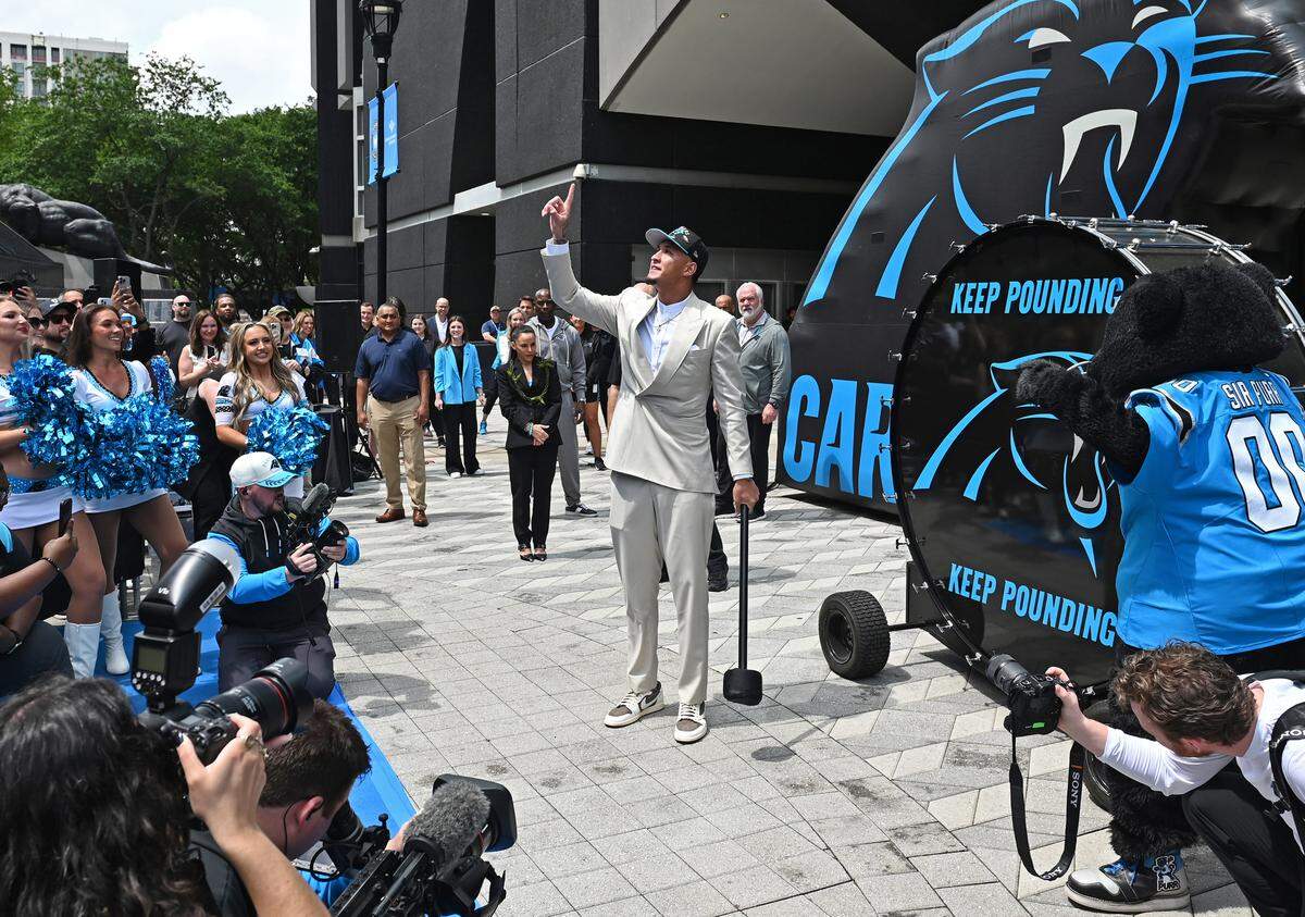 Carolina Panthers 8-pick WR Tetairoa McMillan, center, points to the sky as he prepares to hit the Keep Pounding drum to the cheers of fans at Bank of America Stadium on Friday, April 25, 2025.