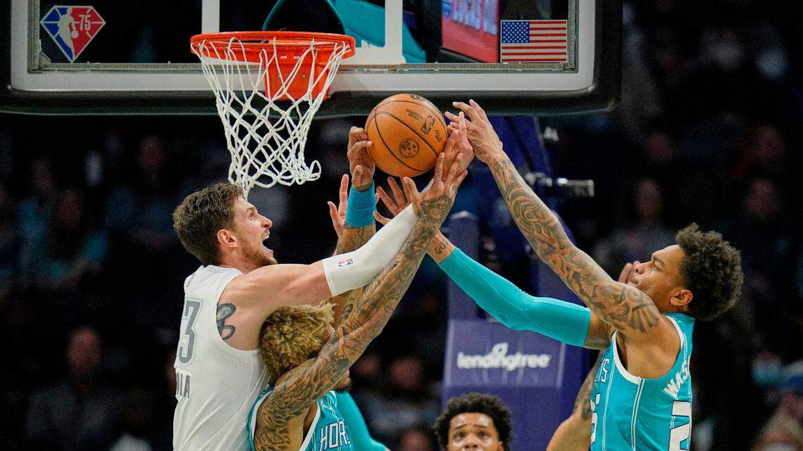Oklahoma City Thunder center Mike Muscala, left, vies for a rebound with Charlotte Hornets guard Kelly Oubre Jr. (12) and forward P.J. Washington, right, as Hornets forward Miles Bridges watches during the first half of an NBA basketball game Friday, Jan. 21, 2022, in Charlotte, N.C. (AP Photo/Rusty Jones)