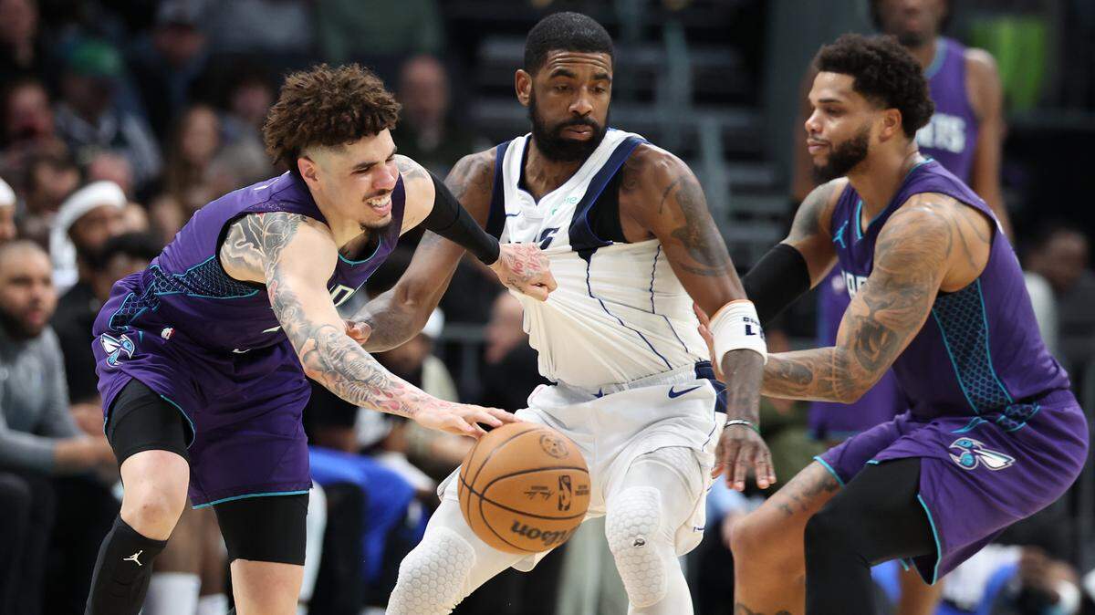 Charlotte Hornets guard LaMelo Ball, left, tries to maintain control of the ball against Dallas Mavericks guard Kyrie Irving, center, as teammate Miles Bridges helps the cause. The Hornets edged Dallas, 110-105, Monday, for their third straight win.
