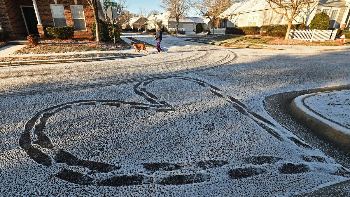 Holly Strack walks her dogs, Tyson and Benson past a heart created in the snow dusted street in the Village of Lake Park in Union County on Wednesday, January 22, 2025.